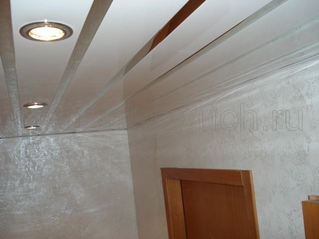 Общий вид коридора с оклеянными обоями стен, устройством подвесного реечного потолка с точечными светильниками, монтажом дверного блока с дверью, доборами и наличниками