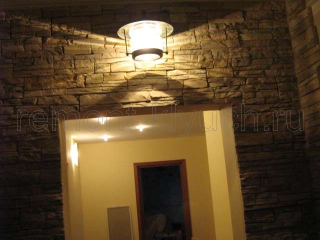 Общий вид стены коридора, облицованной искусственным камнем и с установленным настенным светильником