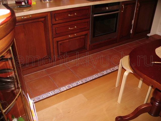 Вид напольного покрытия на кухне из керамических плиток с бордюром и паркетной доски