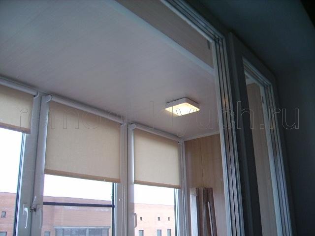 Вид из комнаты на лоджию после ремонта, подвесной потолок со светильниками, установка рулонных штор на окна лоджии