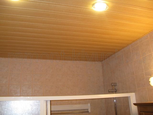 Вид устройства подвесного реечного потолка с встроенными точечными светильниками в санузле и облицованных стен керамической плиткой