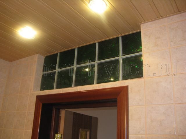 Общий вид устройства подвесного реечного потолка с точечными светильниками в санузле и устройством теклоблоков в нише перегородки, облицованной керамической плиткой, монтаж дверного блока