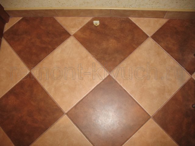 Вид готового напольного покрытия на кухне из керамических плиток стандартного размера с затиркой швов, выложенных по диагонали, устройство напольного керамического бордюра