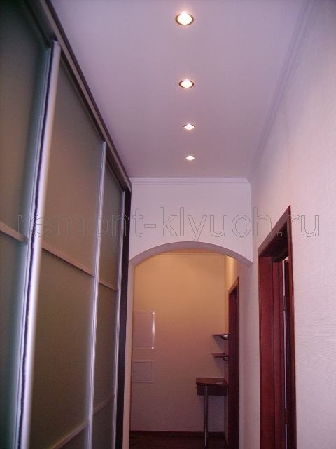Общий вид коридора с освещением точечных светильников подвесного потолка, фигурным арочным проемом, шкафом-купе