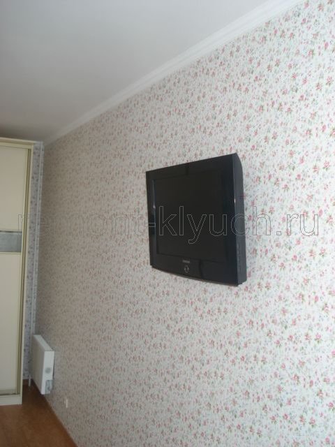 Вид оклеянной стены в гостинной комнате обоями с рисунком, установа радиатора отопления, навеска телевизора на стену