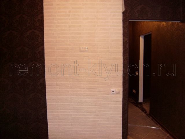 Вид готовой стены в коридоре, скомбинированной из оклейки обоев с рисунком и декоративной облицовкой плиткой, установка выключателей, розеток