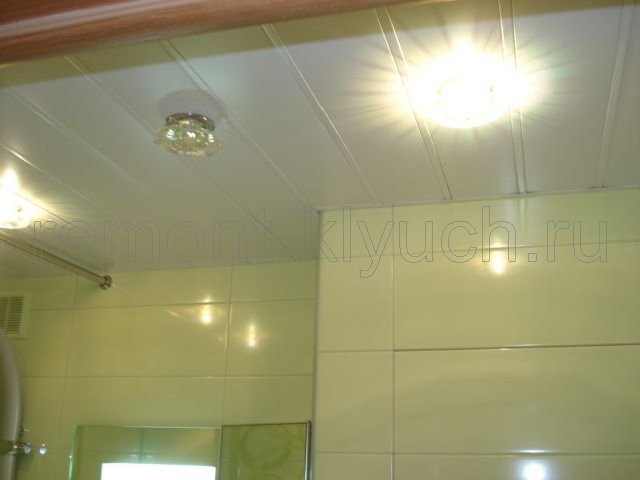 Готовый вид установленного реечного потолка с встроенными светильниками и облицованных стен керамической плиткой с затиркой швов